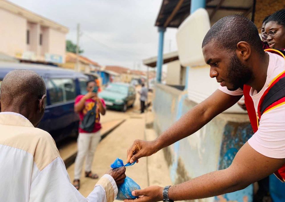 A volunteer handing a food package to a community member.